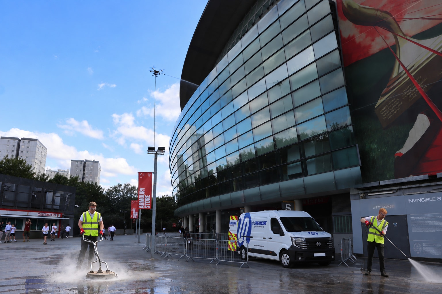 Streamline® technicians cleaning a glass stadium exterior with a van-mounted system, surface cleaner and pressure lance.